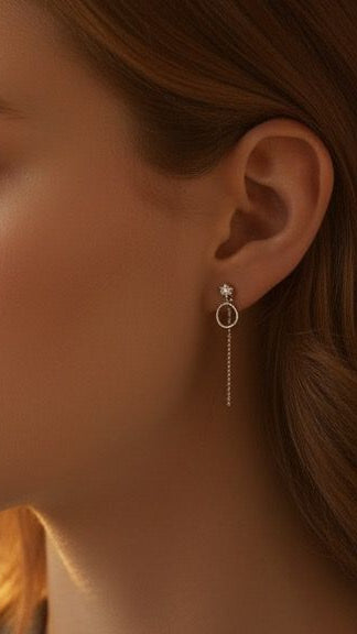 Close-up of a person wearing a silver earring with a chain detail.